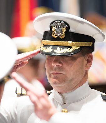 Dale Johnson saluting in Navy dress whites at his retirement ceremony