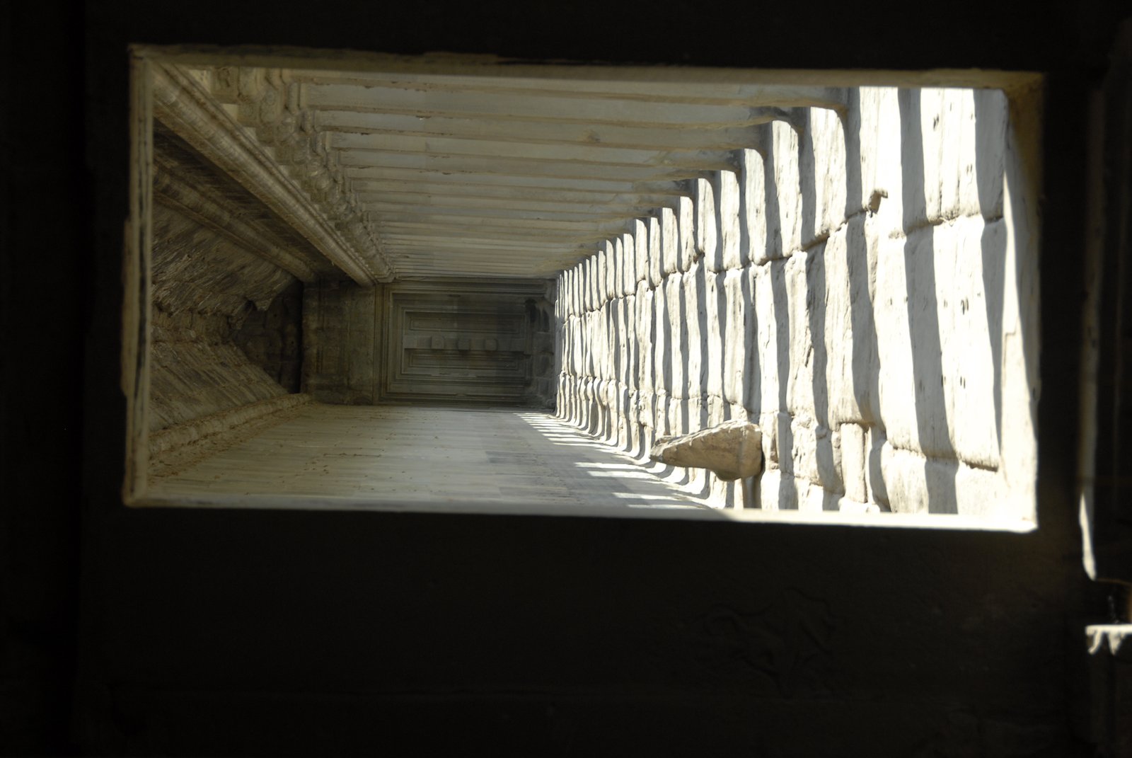 Long stone corridor at Angkor Wat with sunlight and columns, Cambodia