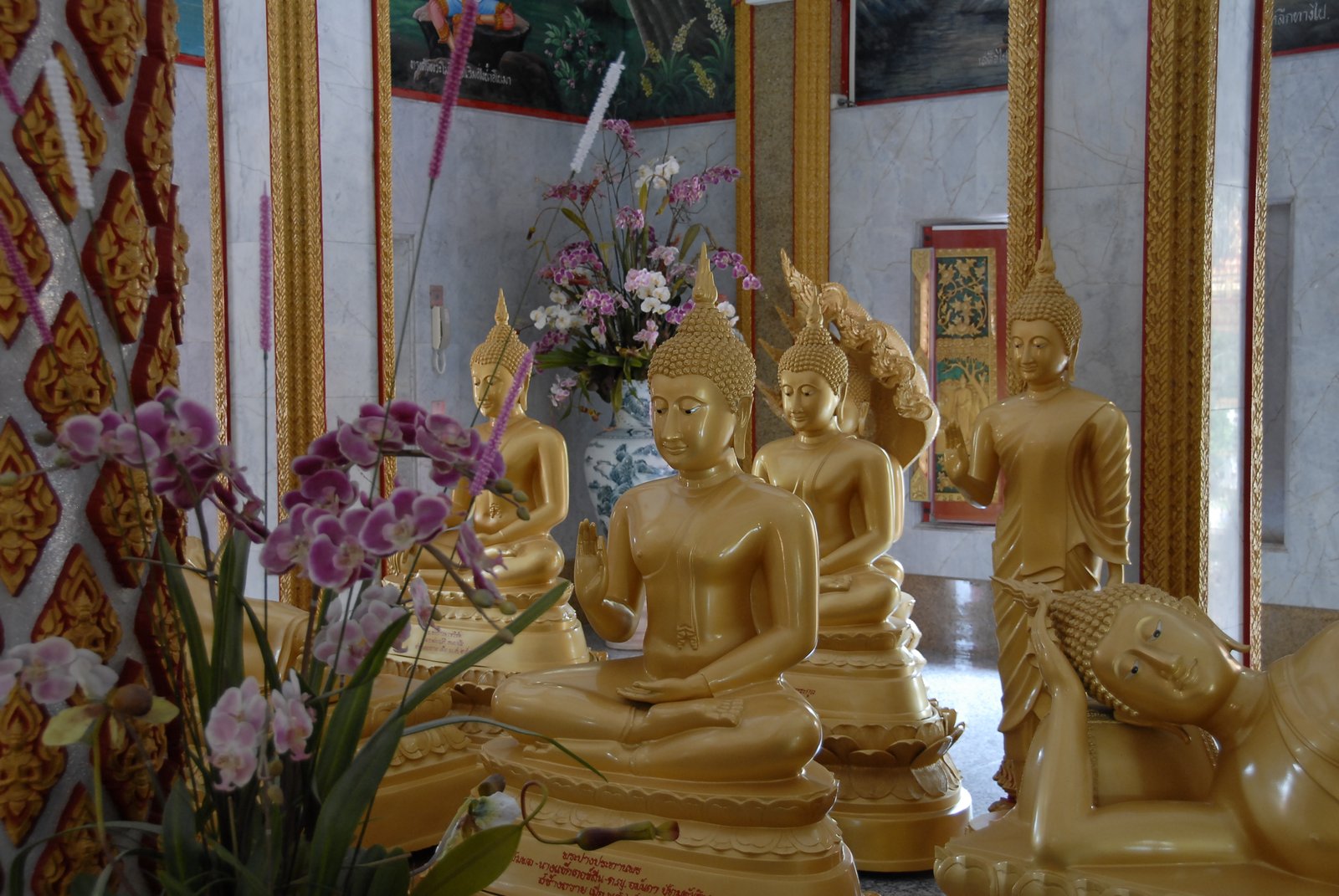 Golden Buddha statues in a Thai temple with orchids