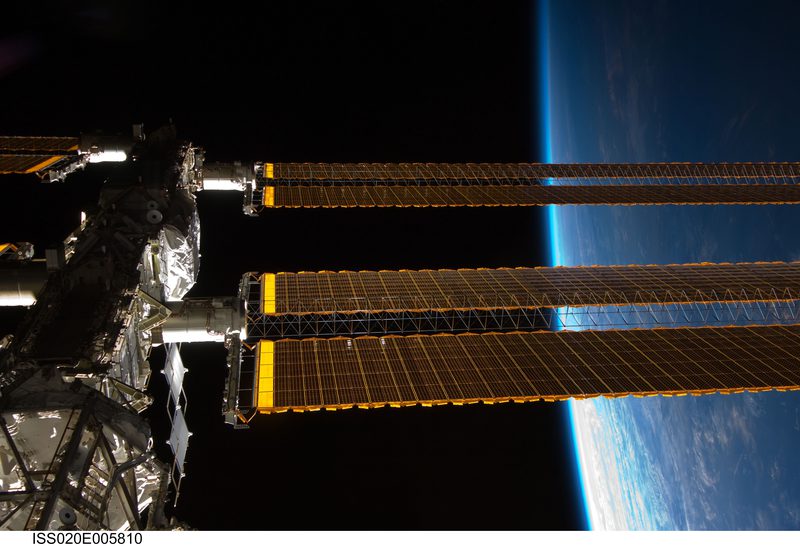 ISS photovoltaic solar array wings with Earth's horizon in background