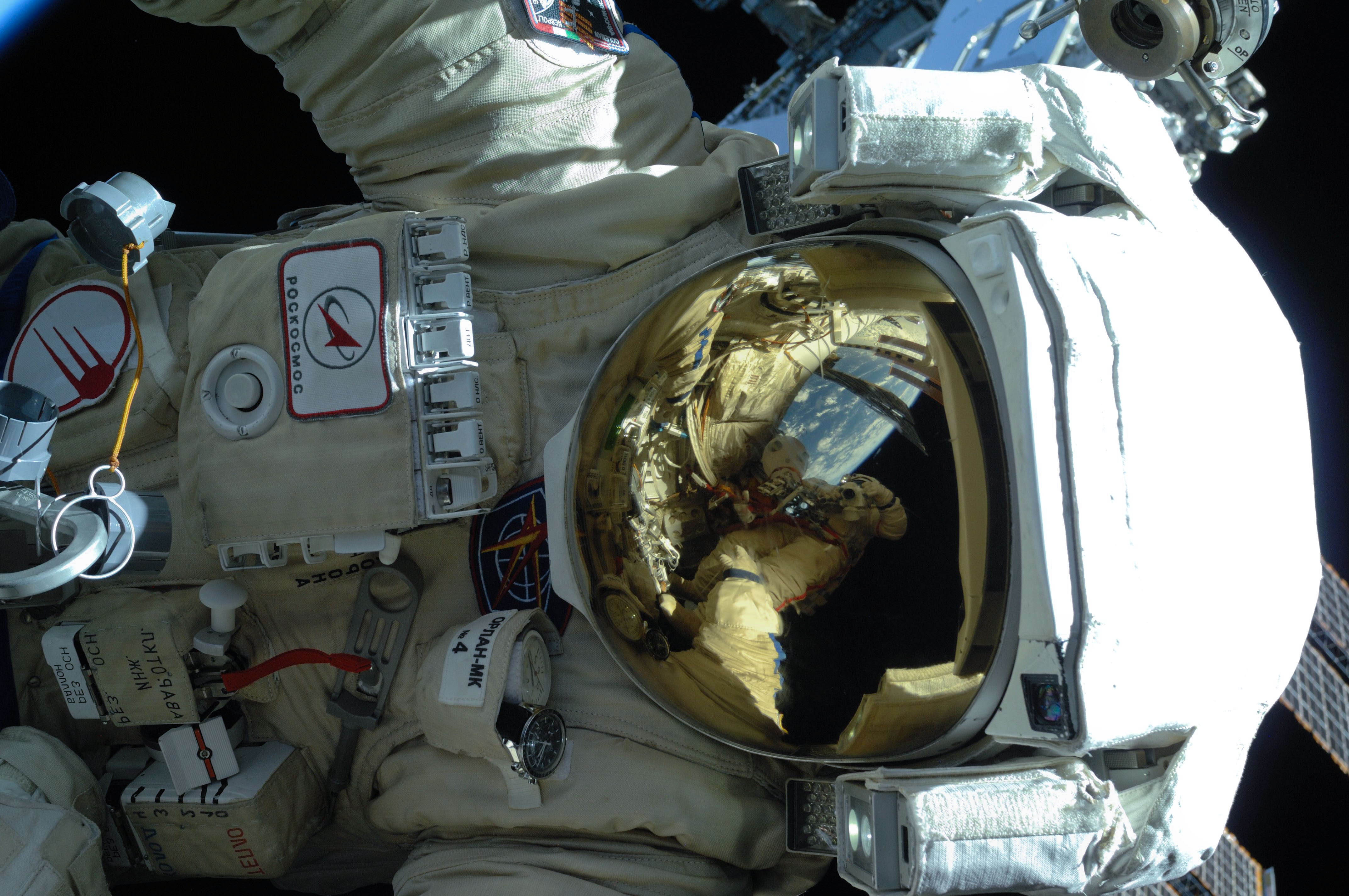 A Russian cosmonaut in an Orlan-MK spacesuit during an extravehicular activity outside the International Space Station, February 2011. Earth is reflected in the visor.